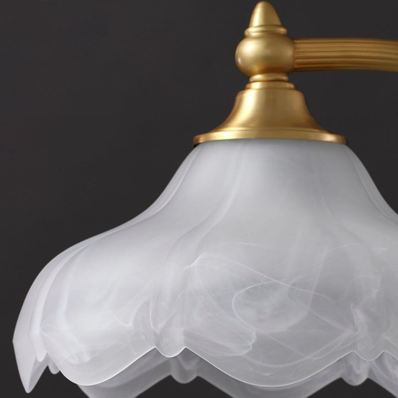 Luminária de mesa retro em metal dourado e vidro com cúpula em formato de pétalas.