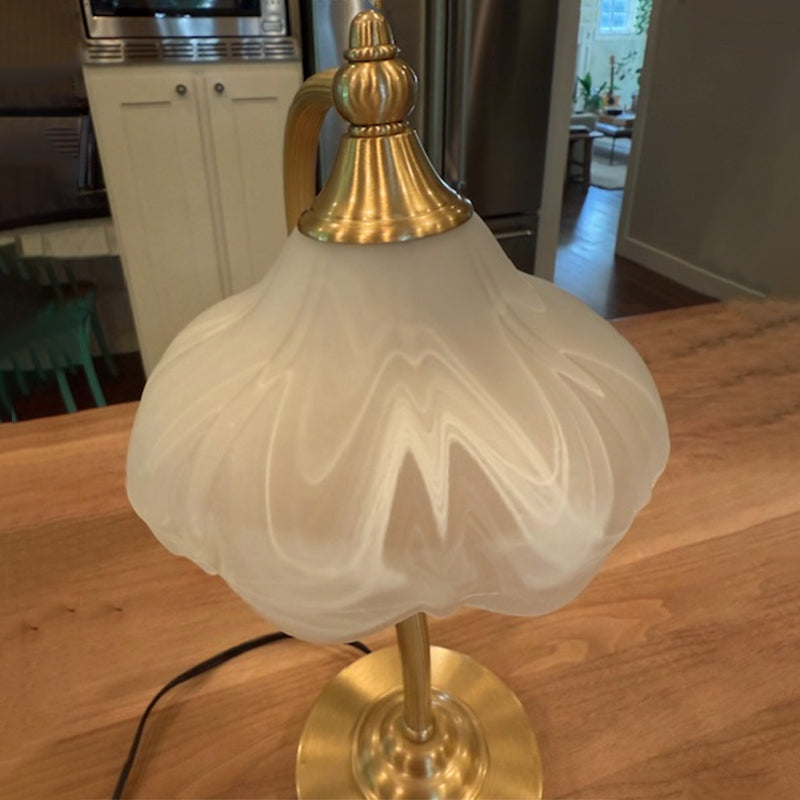 Luminária de mesa retro em metal dourado e vidro com cúpula em formato de pétalas.
