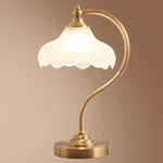 Luminária de mesa retro em metal dourado e vidro com cúpula em formato de pétalas.