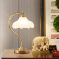 Luminária de mesa retro em metal dourado e vidro com cúpula em formato de pétalas.
