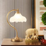 Luminária de mesa retro em metal dourado e vidro com cúpula em formato de pétalas.