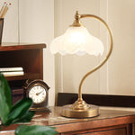 Luminária de mesa retro em metal dourado e vidro com cúpula em formato de pétalas.
