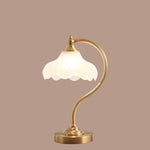 Luminária de mesa retro em metal dourado e vidro com cúpula em formato de pétalas.