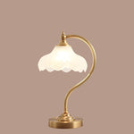 Luminária de mesa retro em metal dourado e vidro com cúpula em formato de pétalas.