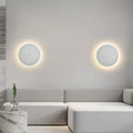 Luminária de parede LED circular com design minimalista e acabamento em aço escovado.