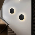 Luminária de parede LED circular com design minimalista e acabamento em aço escovado.
