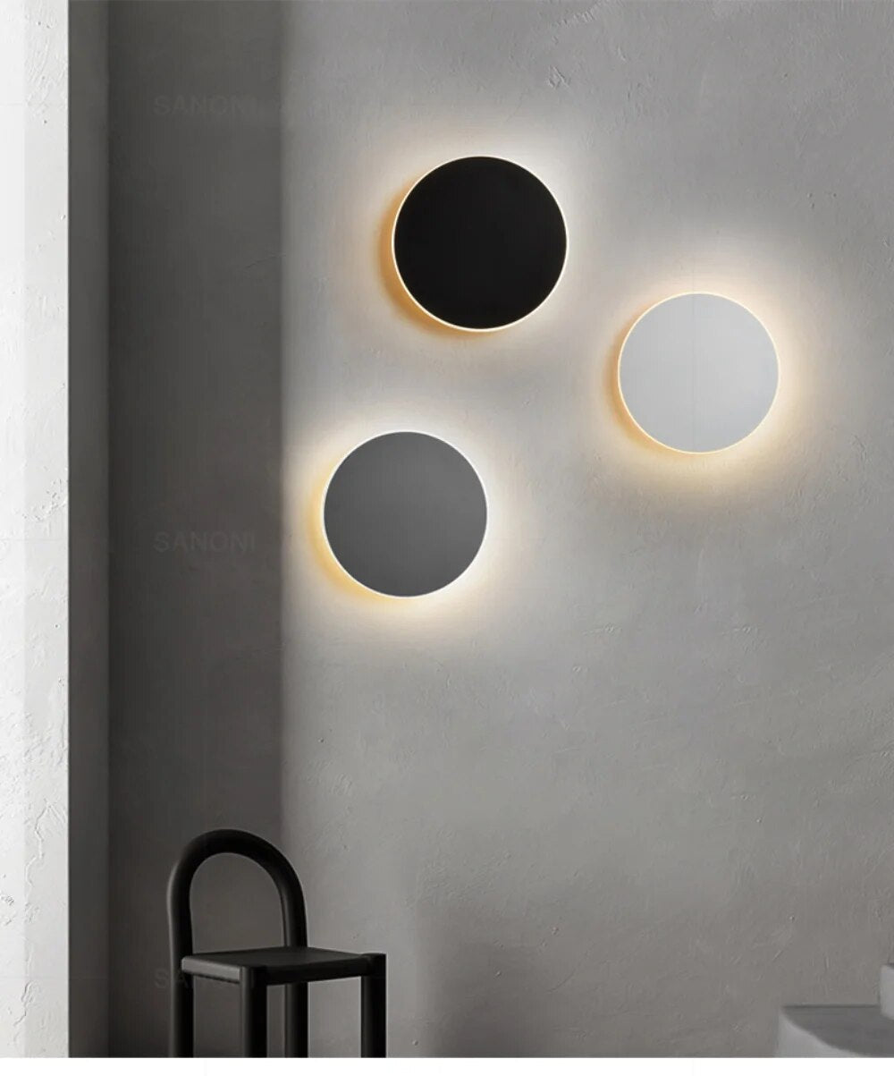 Luminária de parede LED circular com design minimalista e acabamento em aço escovado.