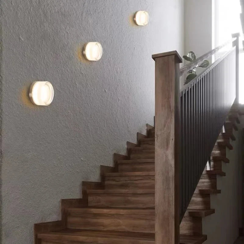 Luminária de parede circular contemporânea com iluminação difusa e acabamento minimalista em metal polido.
