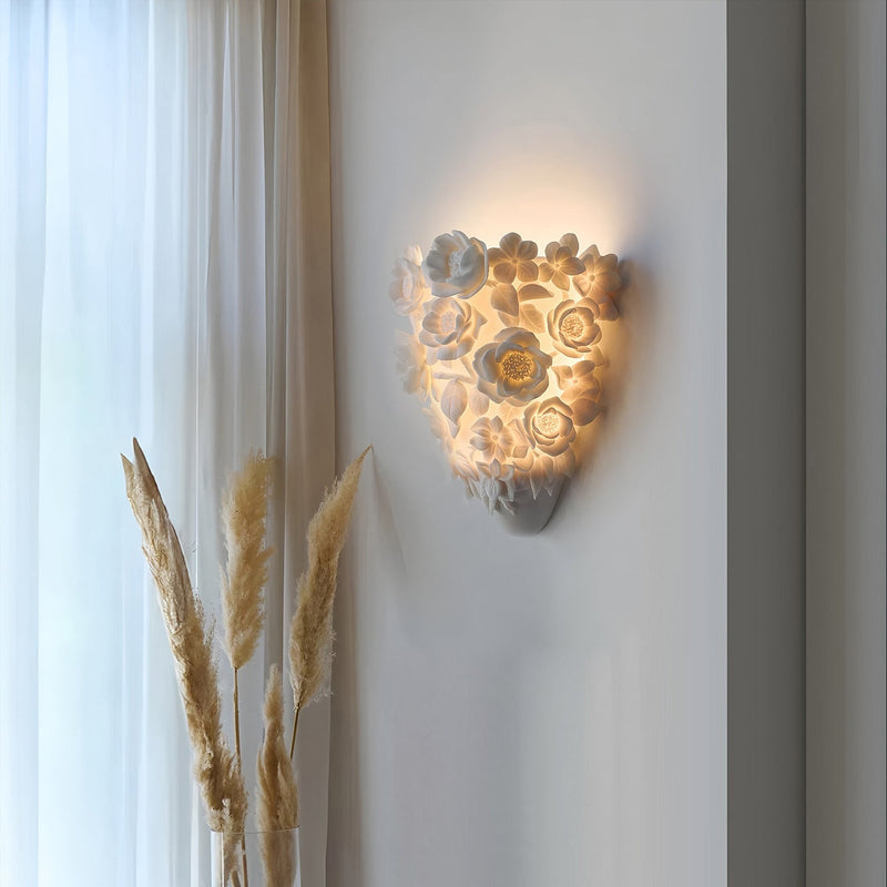 Luminária de parede em cerâmica artesanal com delicadas flores em relevo e iluminação suave para um toque de elegância e charme.