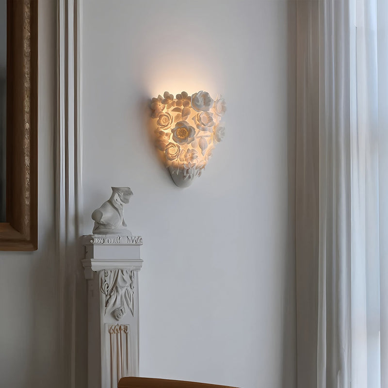 Luminária de parede em cerâmica artesanal com delicadas flores em relevo e iluminação suave para um toque de elegância e charme.