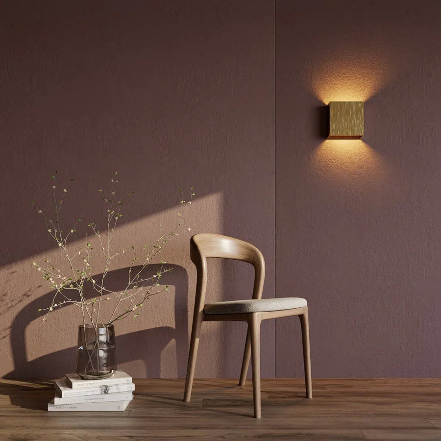 Luminária de parede em metal escovado com iluminação suave e design minimalista para ambientes sofisticados.