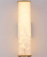 Luminária de parede em pedra refinada com iluminação suave e design escultórico contemporâneo.