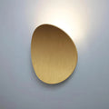 Luminária de parede escultural em metal com iluminação suave e difusa, ideal para ambientes contemporâneos e sofisticados. Dourado