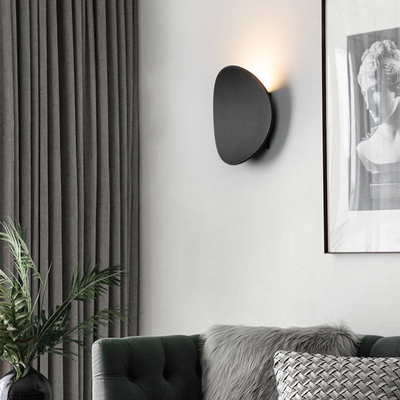 Luminária de parede escultural em metal com iluminação suave e difusa, ideal para ambientes contemporâneos e sofisticados.
