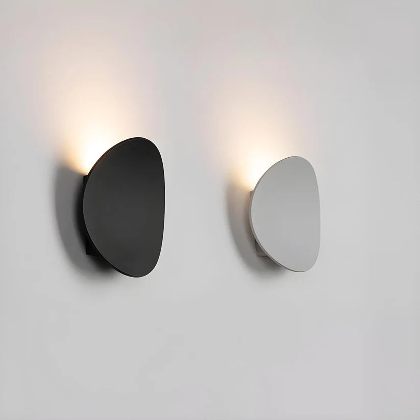 Luminária de parede escultural em metal com iluminação suave e difusa, ideal para ambientes contemporâneos e sofisticados.