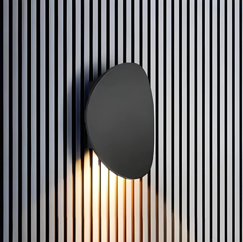 Luminária de parede escultural em metal com iluminação suave e difusa, ideal para ambientes contemporâneos e sofisticados.