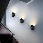 Luminária de parede escultural em metal com iluminação suave e difusa, ideal para ambientes contemporâneos e sofisticados.
