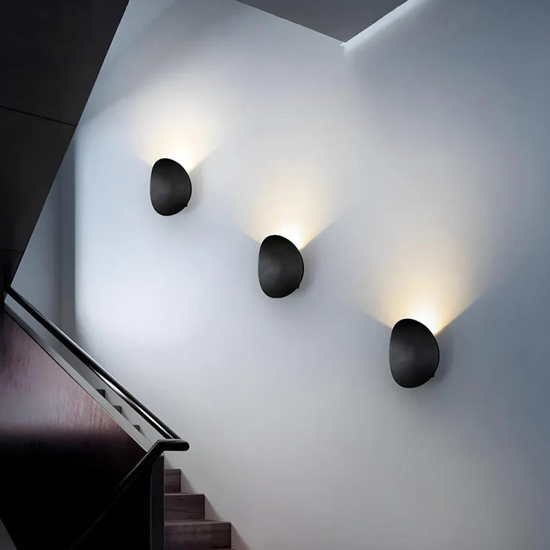 Luminária de parede escultural em metal com iluminação suave e difusa, ideal para ambientes contemporâneos e sofisticados.