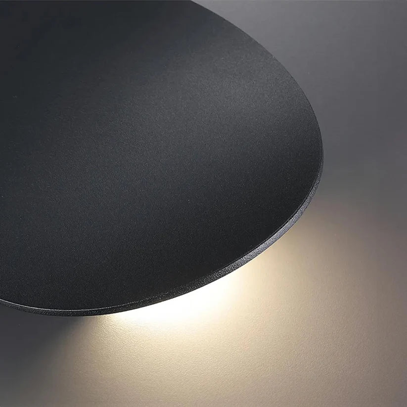 Luminária de parede escultural em metal com iluminação suave e difusa, ideal para ambientes contemporâneos e sofisticados.