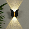 Luminária de parede externa em formato de borboleta, transmitindo um toque de charme contemporâneo e iluminação suave e envolvente. Preto