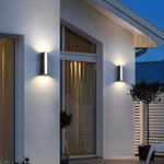 Luminária de parede externa moderna com iluminação bidirecional e design minimalista para ambientes sofisticados.
