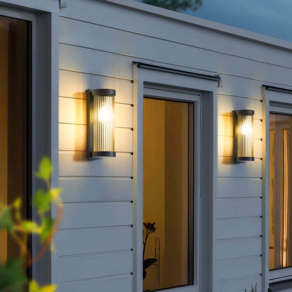 Luminária externa cilíndrica de metal e vidro, resistente à água IP65 com design moderno.
