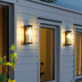 Luminária externa cilíndrica de metal e vidro, resistente à água IP65 com design moderno.