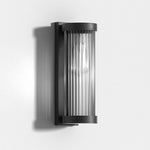 Luminária externa cilíndrica de metal e vidro, resistente à água IP65 com design moderno.
